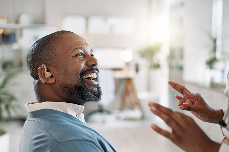 Employee with hearing aid interacting with another person using sign language to communicate