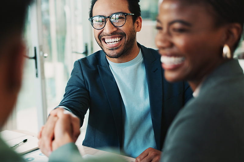 Smiling person with glasses shaking hands with someone