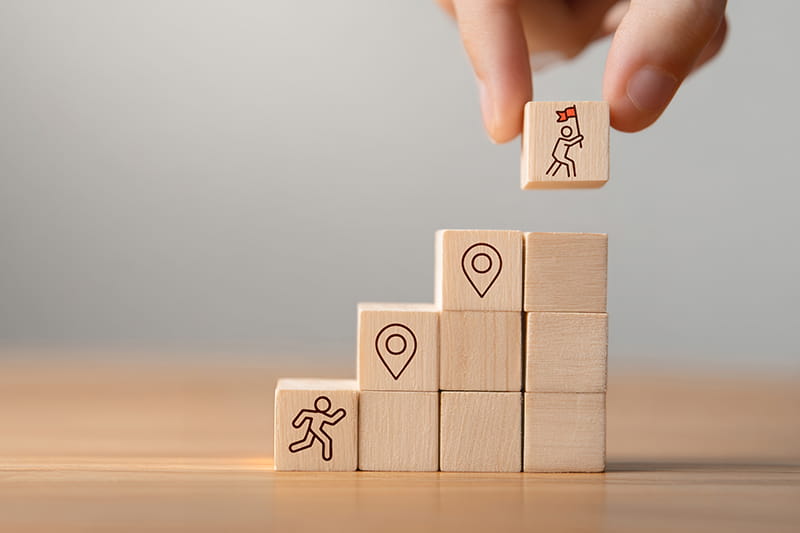 Blocks stacked with icons and fingers holding the top block