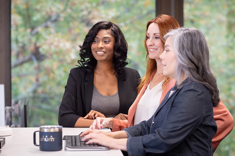 3 employees standing at a computer looking at the screen