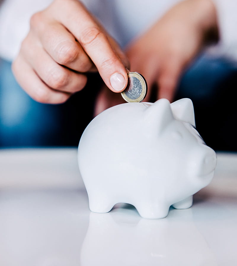 Person putting a coin in a piggy bank