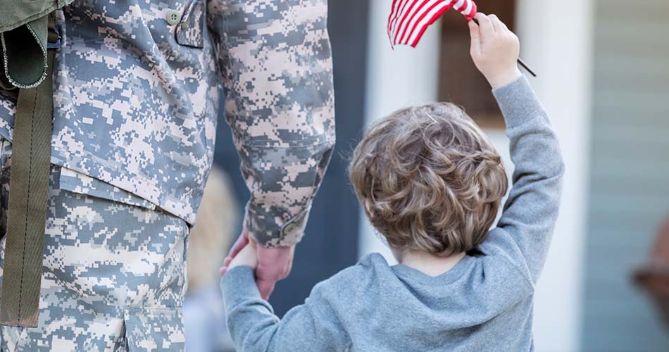 Rear view of boy holding hands with military dad